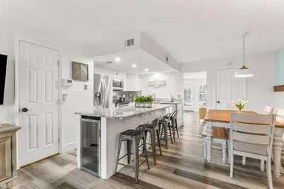 a kitchen and dining room with a large island with bar stools at 4BD Resort Home Golf Cart Inc 11 Pools in Panama City Beach