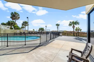 a patio with a swimming pool and a chair at 1st Floor Resort Condo! No Elevators! Free Beach Chair Service! by Dolce Vita Getaways PCB in Panama City Beach