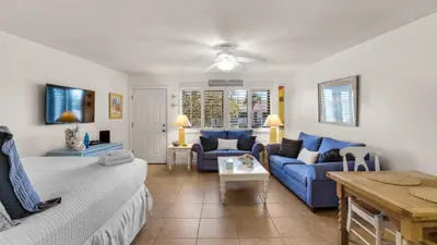 a living room with a bed and a blue couch at Hidden Beach 216 in Santa Rosa Beach