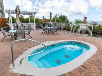 a swimming pool with a table and chairs and an umbrella at Twin Palms #1501A in Panama City Beach