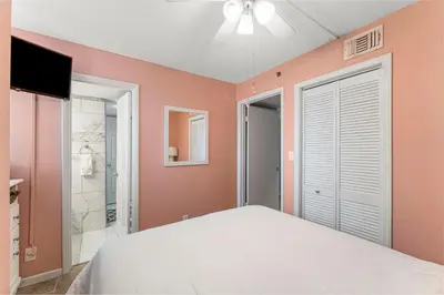 a bedroom with a white bed and a bathroom at Fun N The Sun at Sunbird #1102W by InJoy Vacations in Panama City Beach