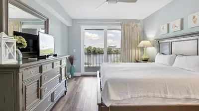 a bedroom with a bed and a television and a balcony at Laketown Wharf #0109 in Panama City Beach