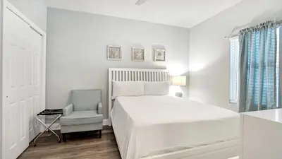 a white bedroom with a bed and a chair at Laketown Wharf #0109 in Panama City Beach