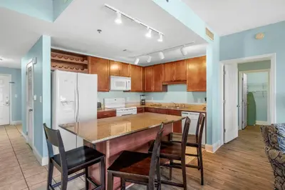 a kitchen with wooden cabinets and a large island with chairs at Laketown Wharf #0201 in Panama City Beach