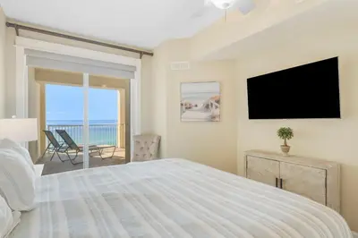 a bedroom with a large bed and a flat screen tv at Grand Panama #1-1001 in Panama City Beach