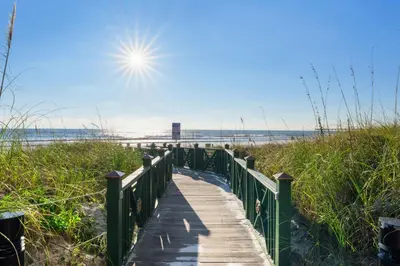 a boardwalk to the beach with the sun in the sky at Grand Panama #1-1704 in Panama City Beach