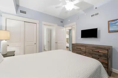 a bedroom with a white bed and a flat screen tv at Grand Panama #1-1308 in Panama City Beach