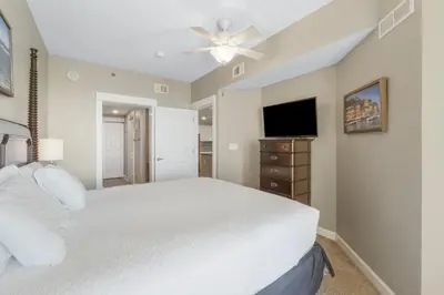 a bedroom with a white bed and a flat screen tv at Grand Panama #1-1308 in Panama City Beach