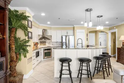 a kitchen with white cabinets and bar stools at Grand Panama #1-2201 in Panama City Beach