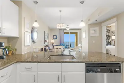 a kitchen with a sink and a living room at Grand Panama #1-1903 in Panama City Beach
