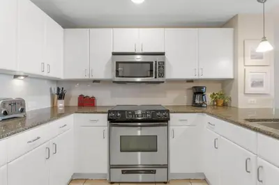 a kitchen with white cabinets and a stove and microwave at Grand Panama #1-1903 in Panama City Beach
