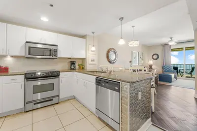 a kitchen with stainless steel appliances and a living room at Grand Panama #1-1903 in Panama City Beach