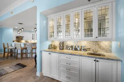 a kitchen with white cabinets and a dining room with a table at Grand Panama #1-2101 in Panama City Beach