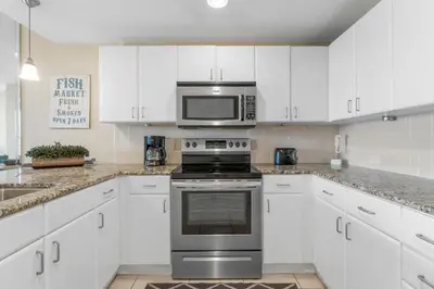a kitchen with white cabinets and a stove and a microwave at Grand Panama #2-0505 in Panama City Beach