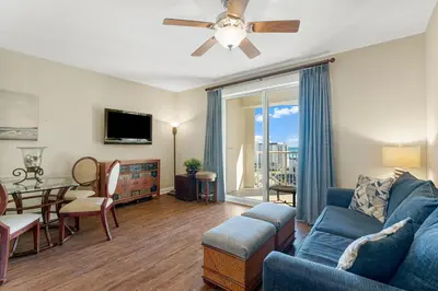 a living room with a blue couch and a dining room at Grand Panama #2-0603 in Panama City Beach