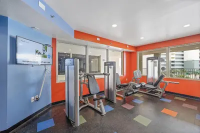a gym with two tread machines in a room with orange walls at Shores Of Panama #1205 in Panama City Beach