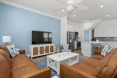 a living room with a couch and a flat screen tv at Spectacular 3br 4ba w/ Private Pool, 2 Min Walk to Beach - Sleeps 15! in Panama City Beach