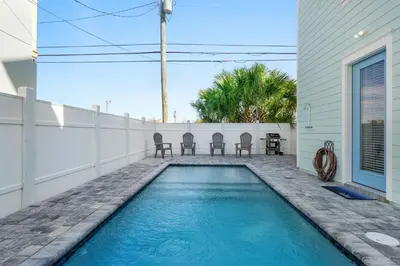 a swimming pool with chairs and a table on a house at Spectacular 3br 4ba w/ Private Pool, 2 Min Walk to Beach - Sleeps 15! in Panama City Beach