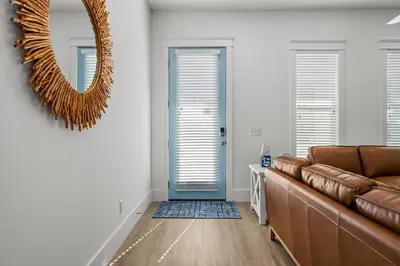 a living room with a brown couch and a mirror at Spectacular 3br 4ba w/ Private Pool, 2 Min Walk to Beach - Sleeps 15! in Panama City Beach