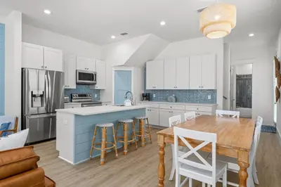 a kitchen with white cabinets and a wooden table at Spectacular 3br 4ba w/ Private Pool, 2 Min Walk to Beach - Sleeps 15! in Panama City Beach