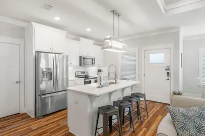 a kitchen with white cabinets and a kitchen island with stools at Laguna Peach: 3BA 2BA retreat for 10! Explore nearby beaches & activities in Panama City Beach