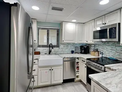 a kitchen with white cabinets and a stainless steel refrigerator at Sunbird Beach Resort 1207 West in Panama City Beach