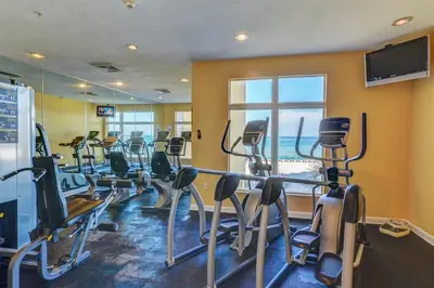 a gym with a row of treadmills and exercise bikes at Beachfront Stunning view 100 ft long swimming pool in Panama City Beach