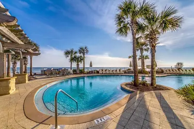 a swimming pool with palm trees and the ocean at Aqua #2209 in Panama City Beach