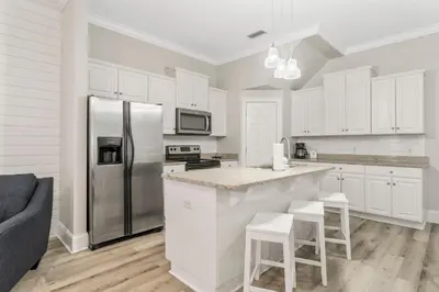a kitchen with white cabinets and a stainless steel refrigerator at Spectacular Gulf Views w/ PRIVATE POOL! Remarkable 3BR 35BA Bedding for 12! in Panama City Beach