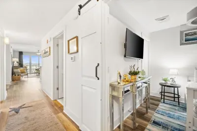 a living room with a white door and a tv at Calypso #3-607 in Panama City Beach