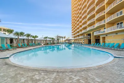 a large swimming pool with blue chairs and a building at Calypso #3-607 in Panama City Beach