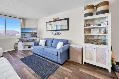 a living room with a blue couch and a desk at Top of the Gulf 418 in Panama City Beach