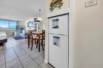 a kitchen and living room with a refrigerator and a table at Top of the Gulf 418 in Panama City Beach