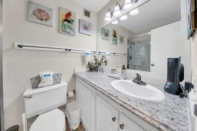 a bathroom with a sink and a toilet and a mirror at Top of the Gulf 418 in Panama City Beach