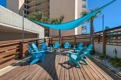 a deck with blue chairs and a hammock at Top of the Gulf 418 in Panama City Beach