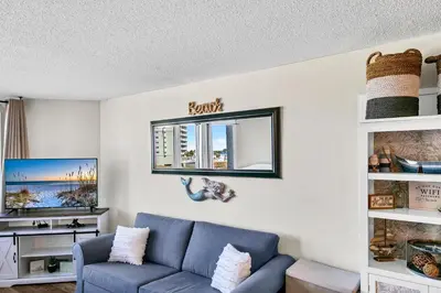 a living room with a blue couch and a window at Top of the Gulf 418 in Panama City Beach