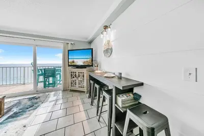 a living room with a table and a view of the ocean at The Summit 1426 in Panama City Beach