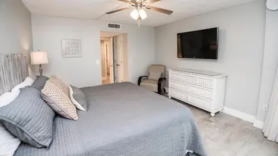 a bedroom with a bed and a flat screen tv at Dunes of Panama E605 2BR 2BA BEACHFRONT condo in Panama City Beach