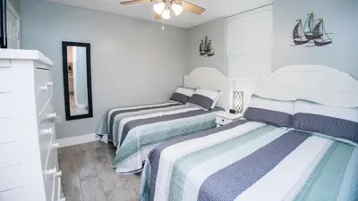 two beds in a small room with blue walls at Dunes of Panama E605 2BR 2BA BEACHFRONT condo in Panama City Beach