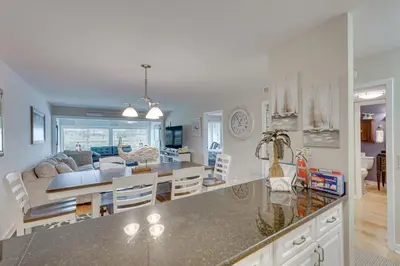 a kitchen and dining room with a table and a living room at Panama City Beach Bay Point Condo Close to Golf! in Panama City Beach