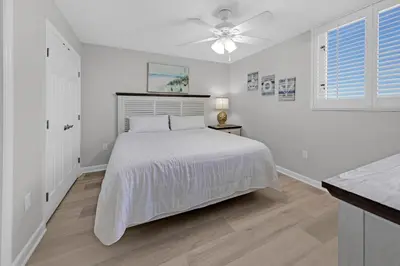 a white bedroom with a bed and a ceiling fan at Sterling Beach #1206 in Panama City Beach