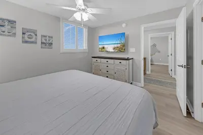 a white bedroom with a bed and a ceiling fan at Sterling Beach #1206 in Panama City Beach
