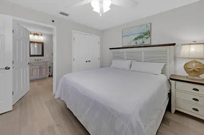 a white bedroom with a large bed and a desk at Sterling Beach #1206 in Panama City Beach