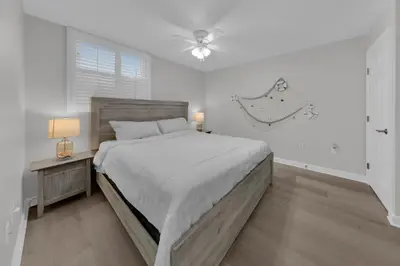 a white bedroom with a large bed and a fan at Sterling Beach #406 in Panama City Beach