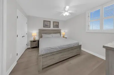 a white bedroom with a bed and a ceiling fan at Sterling Beach #406 in Panama City Beach