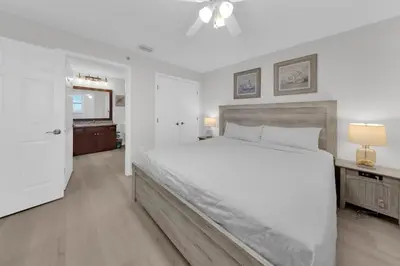 a white bedroom with a large bed and a television at Sterling Beach #406 in Panama City Beach