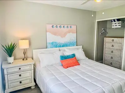 a bedroom with a white bed with an orange pillow at Tropical Gem/5 min beach walk in Panama City Beach