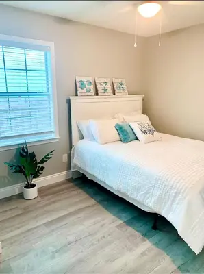a bedroom with a white bed and a potted plant at Tropical Gem/5 min beach walk in Panama City Beach