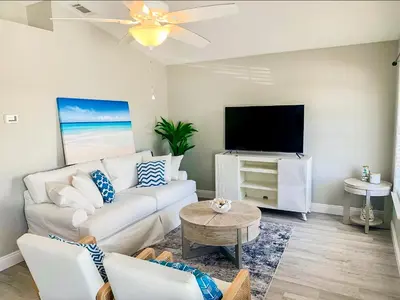 a living room with a white couch and a flat screen tv at Tropical Gem/5 min beach walk in Panama City Beach