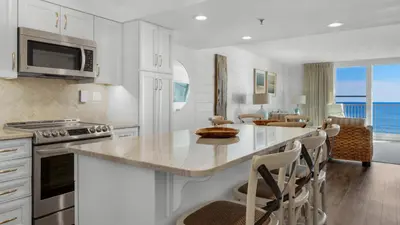 a kitchen with white cabinets and a kitchen island with chairs at BeachCrest 302 Wave and Sea in Santa Rosa Beach